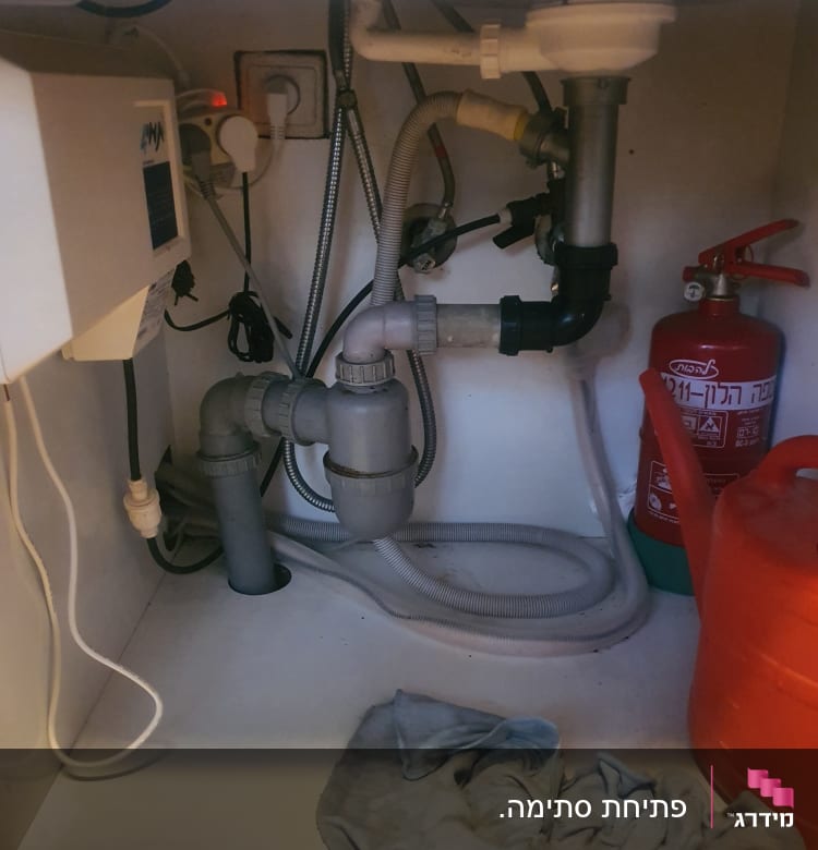 צנרת מתחת לכיור עם ברזים וצינורות